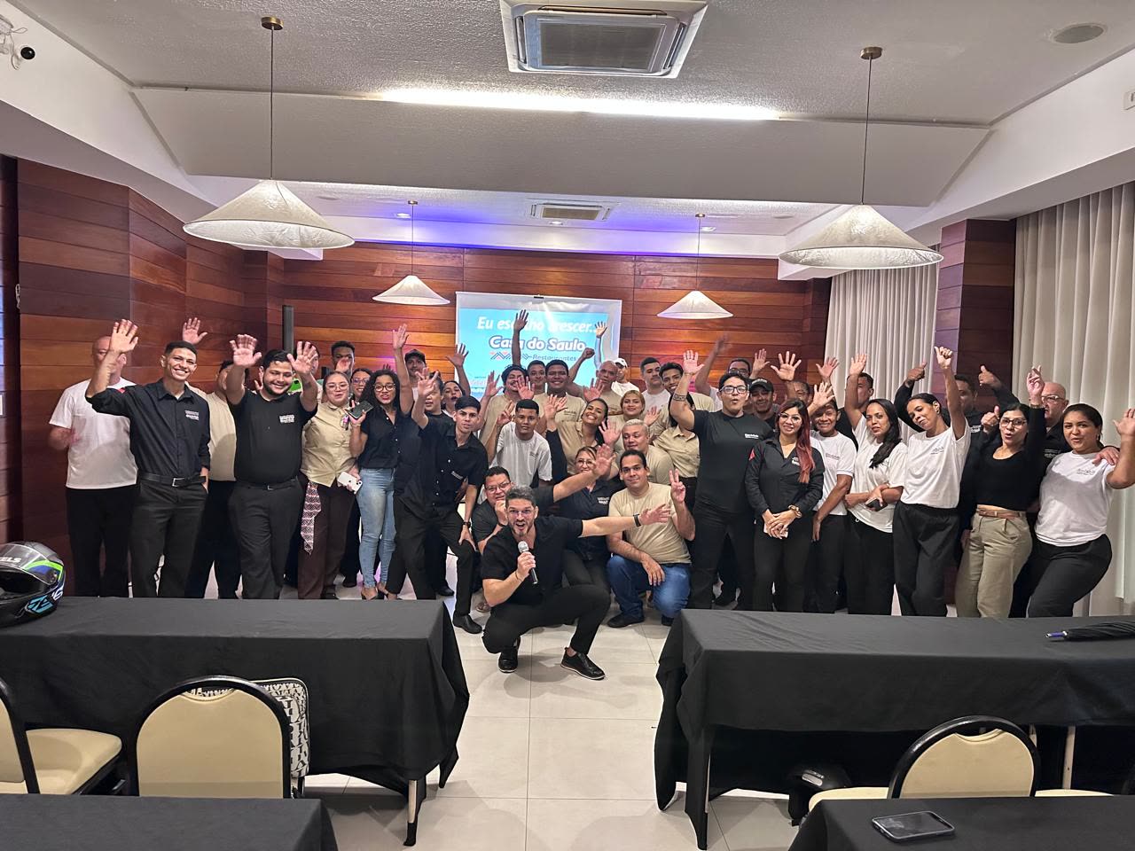 Moysés Carvalho com a turma de participantes de uma imersão, todos acenando e comemorando